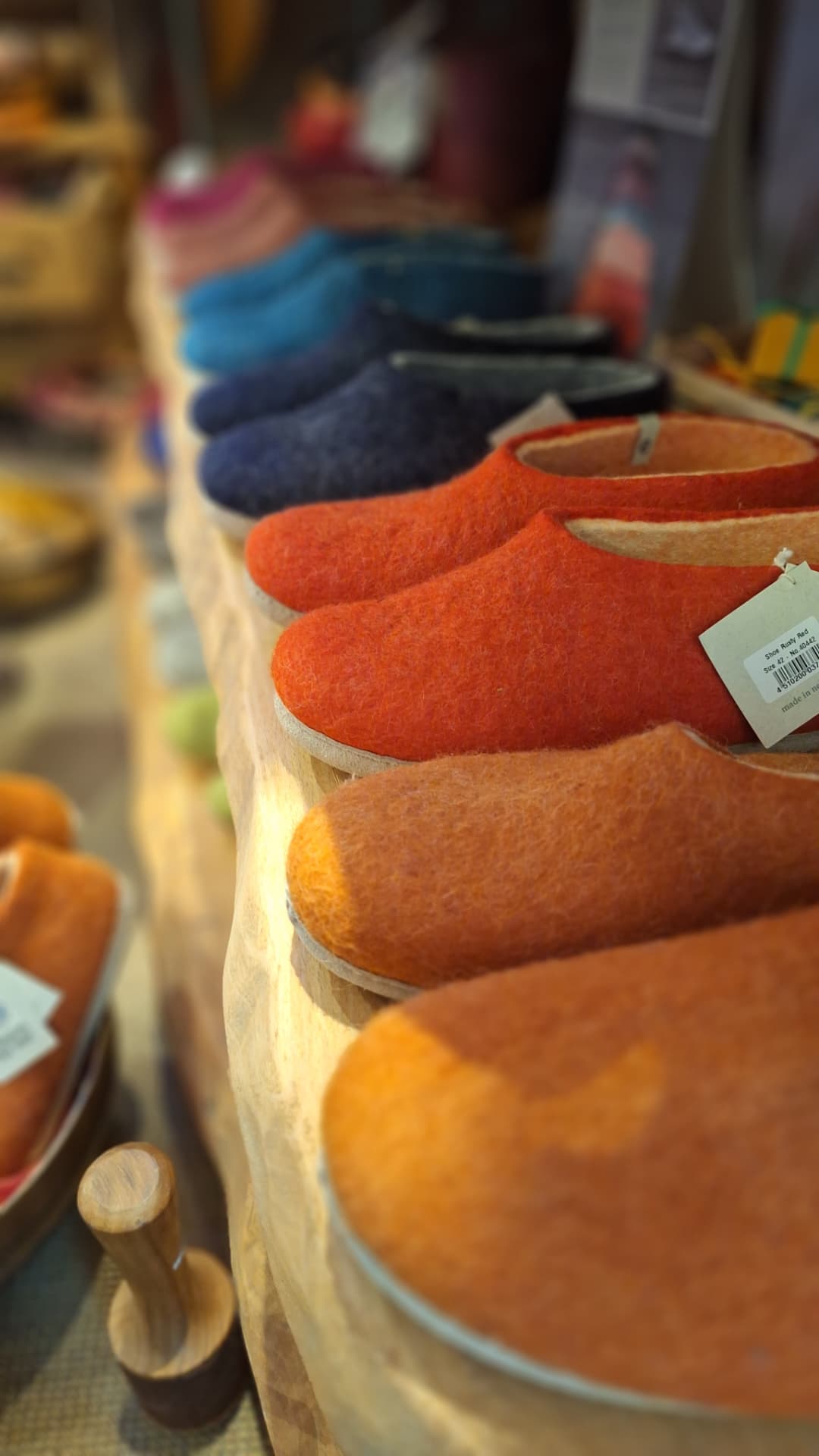 Rangée de chaussons en feutre orange, bleus et rouges chez Luxiol