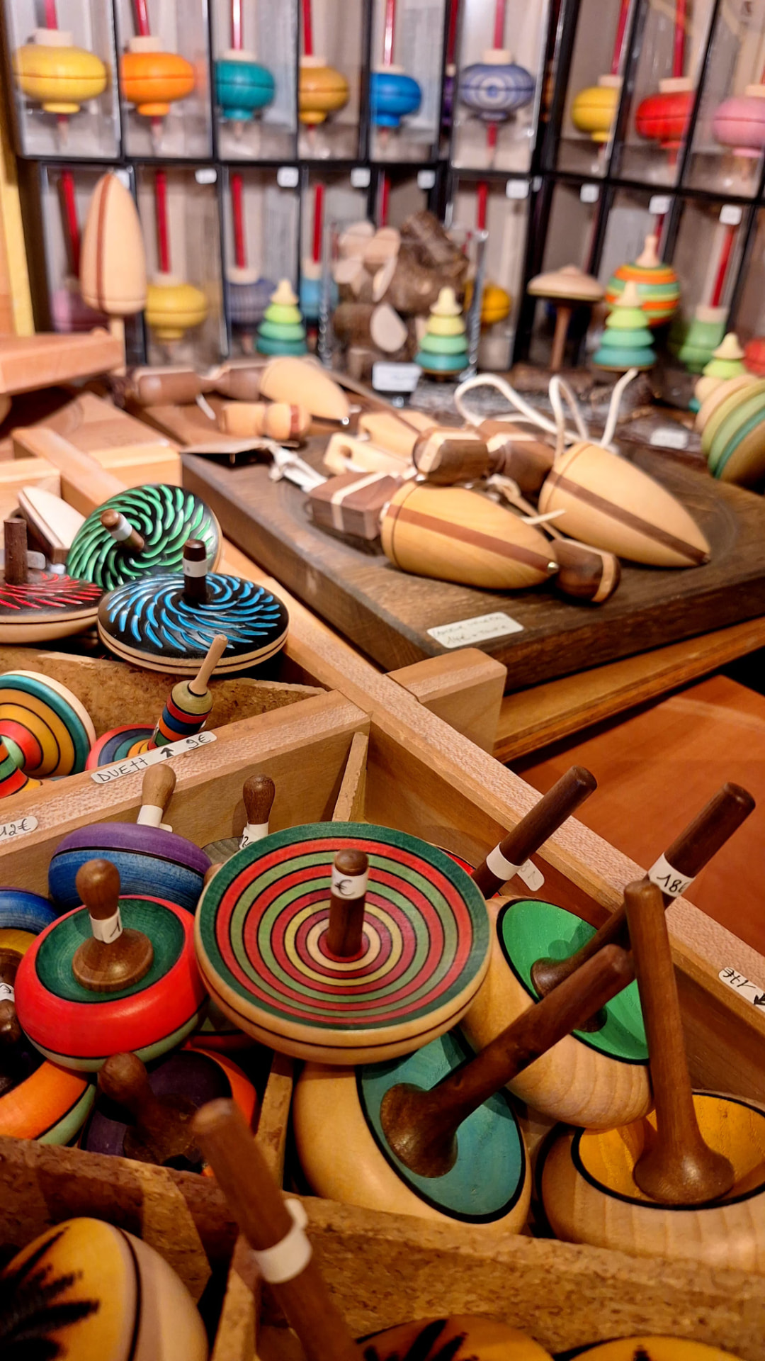Casiers remplis de toupies en bois colorées et toupies à ficelle chez Luxiol