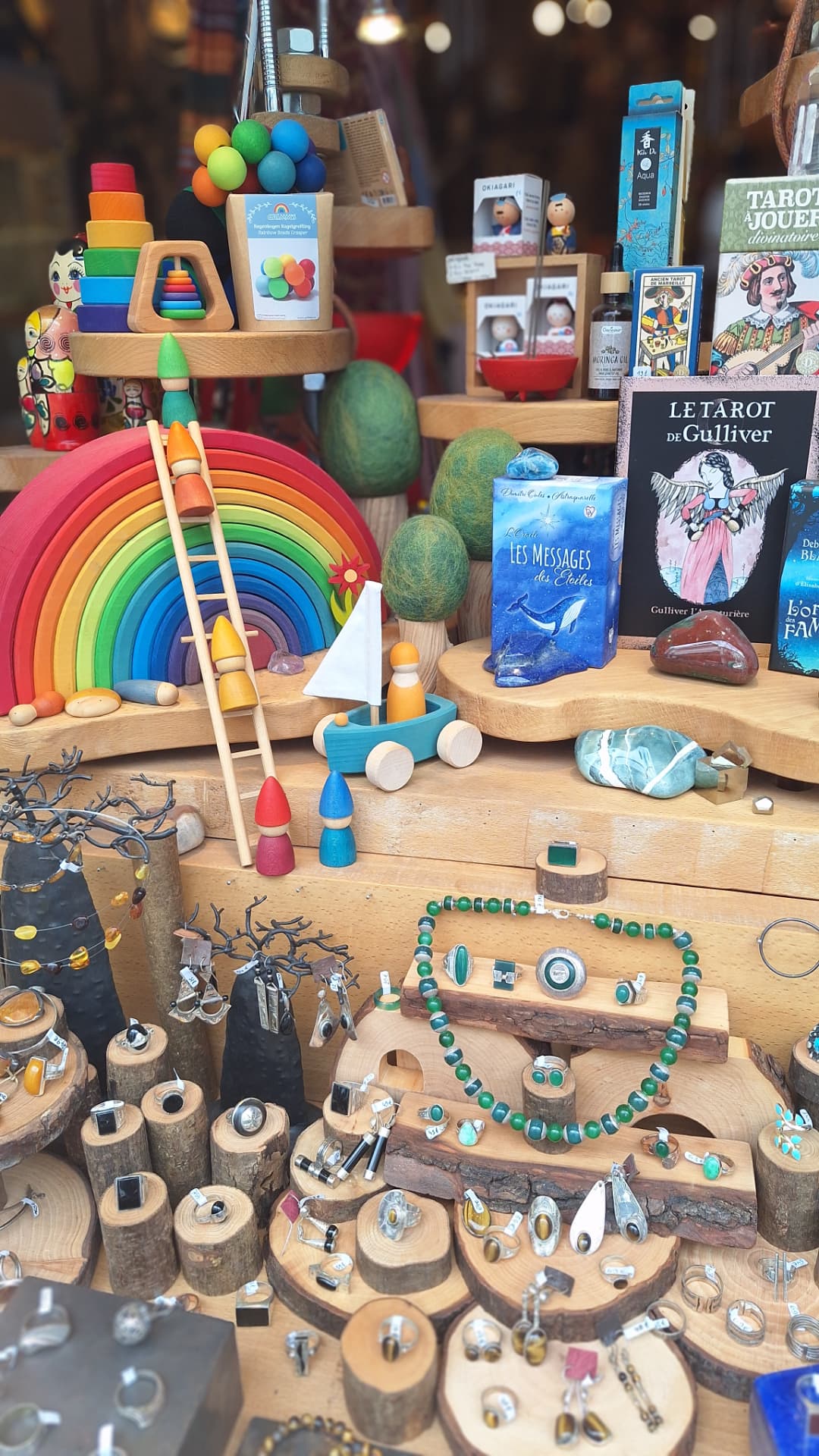 Détail de la vitrine : jouets en bois, oracles et bagues sur rondins chez Luxiol