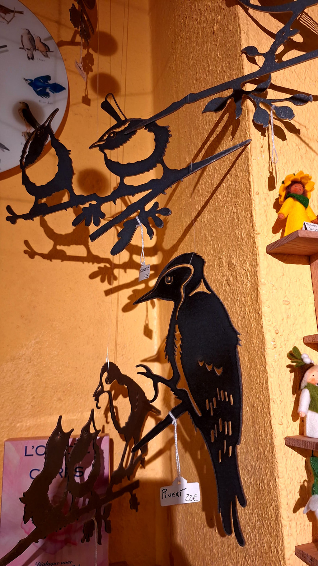 Oiseaux en métal découpé suspendus devant un mur ocre chez Luxiol