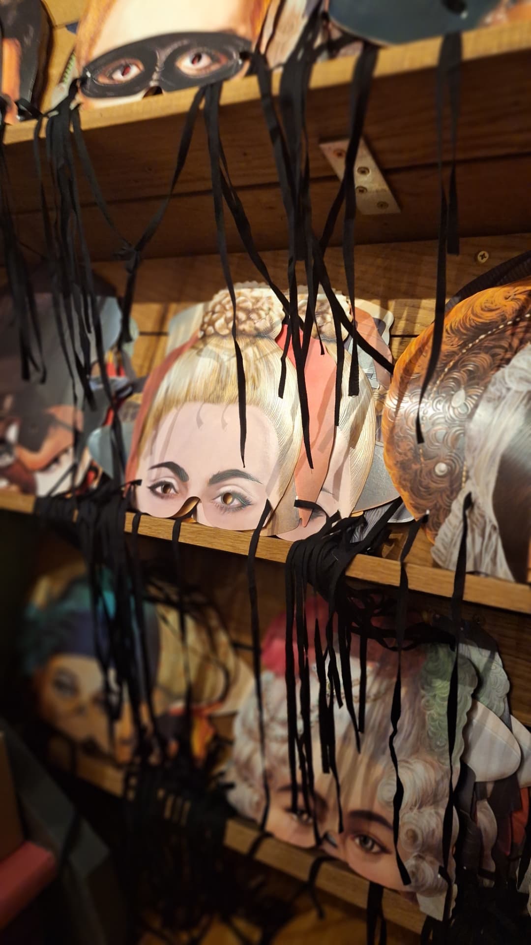 Masques en carton rangés sur des étagères en bois chez Luxiol