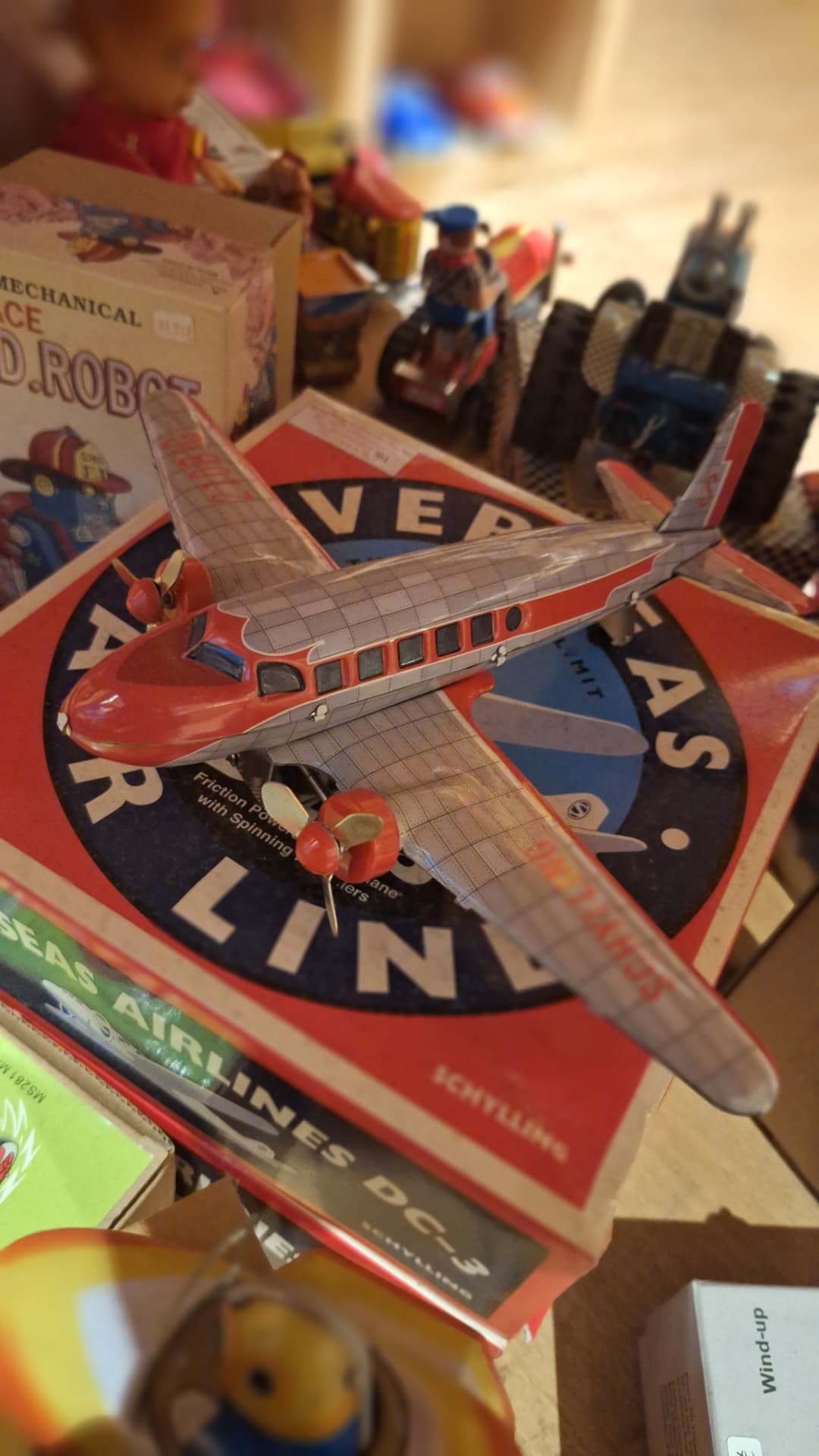 Avion en tôle lithographiée posé sur sa boîte vintage chez Luxiol
