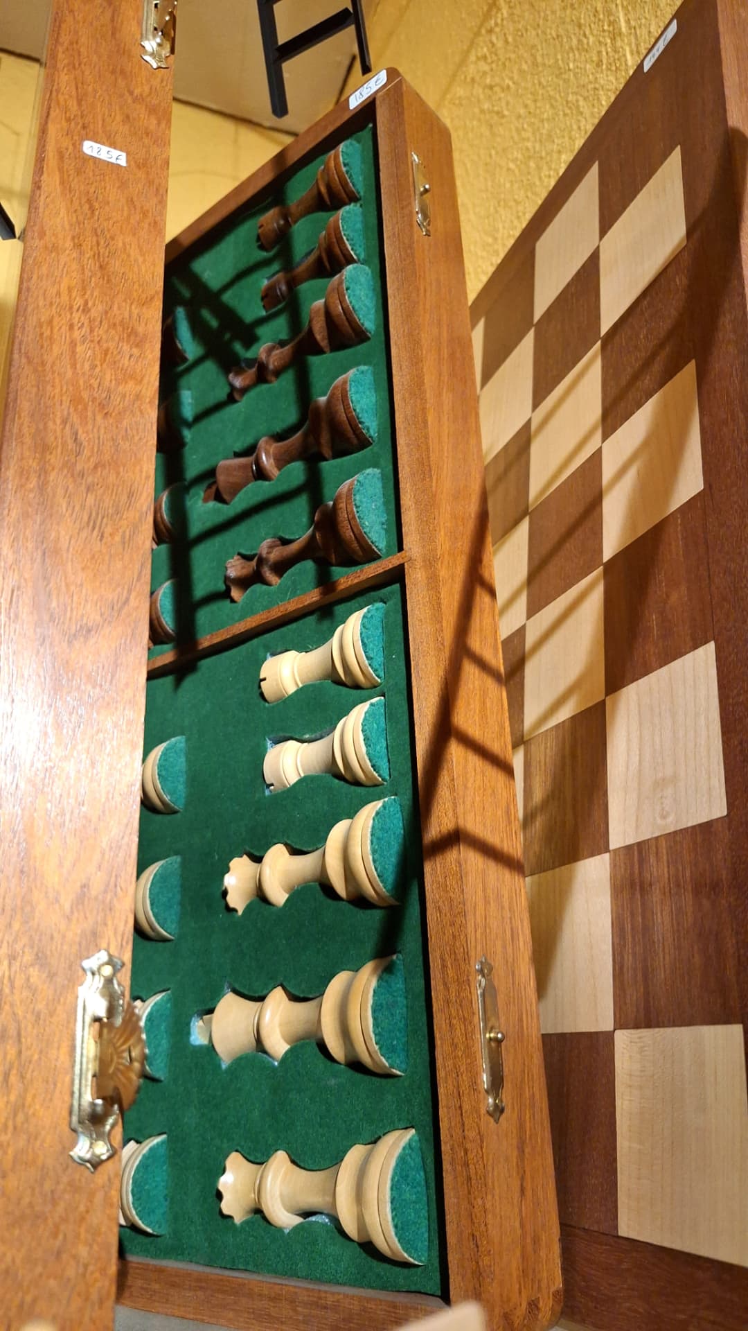 Coffret d'échecs en bois ouvert avec pièces sur feutrine verte chez Luxiol